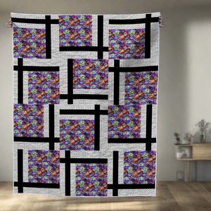 May include: A large quilt with a geometric design. The quilt features squares of colorful floral fabric set within a grid of black lines on a white background. The quilt is hanging on a wooden rod.