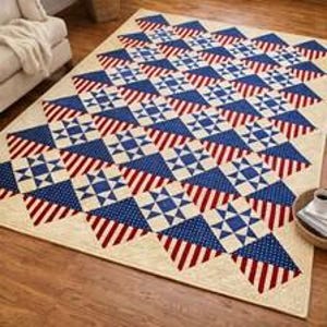 May include: A rectangular quilt featuring a repeating geometric pattern of stars and stripes in red, white, and blue. The design consists of alternating blocks of blue fabric with white stars and red and white striped fabric on a cream background.
