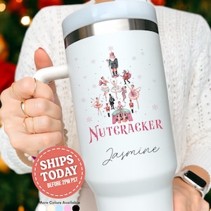 May include: White insulated tumbler with a light blue lid and handle. The tumbler features a Nutcracker-themed design with ballerinas and a nutcracker soldier. The name "Jasmine" is written in cursive below the design. The tumbler is a holiday-themed gift.