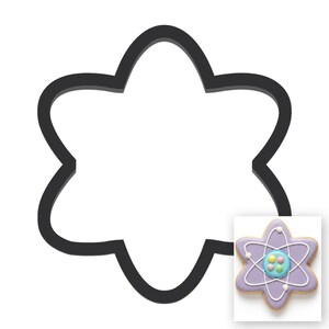 May include: A black, six-pointed star-shaped cookie cutter with rounded edges. An inset image shows a finished cookie shaped like an atom, featuring light purple icing, white piped orbital lines, and a central cluster of small, colorful candy spheres.