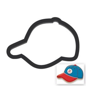 May include: Black baseball cap-shaped cookie cutter. The cutter has a curved brim and a rounded crown, with a small hole at the top. A small image shows a finished cookie in red, blue, and white.