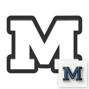 May include: A large, black outlined letter "M" with a white interior. A smaller, gold-colored pin with a blue and white "M" design is in the lower right corner. The pin has a white background.