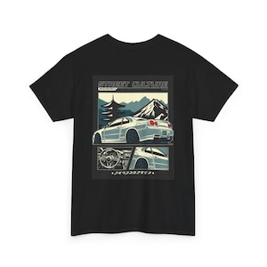 Puede incluir: Camiseta negra con un gráfico de un coche deportivo blanco con un paisaje de montaña y pagoda. El diseño incluye el texto "STREET CULTURE" y texto japonés. El diseño del coche es de estilo ilustración vintage.