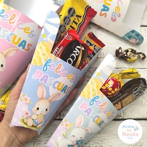 May include: Cone-shaped party favor holders with a pastel blue and pink design, featuring a cartoon bunny, Easter eggs, and the text "Felices Pascuas." The holders are filled with various wrapped candies and chocolate bars.