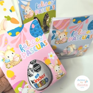 Puede incluir: Cajas de regalo de Pascua en rosa y azul, decoradas con conejitos, huevos de Pascua y la frase "Felices Pascuas". Una caja contiene un huevo de chocolate Kinder Huevo.