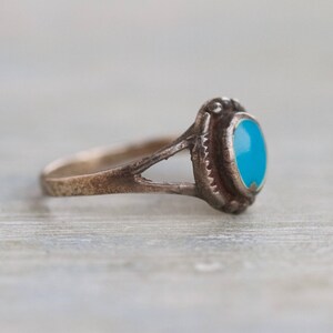 May include: A silver ring with a turquoise stone set in a bezel setting. The ring has a simple band and a delicate design.