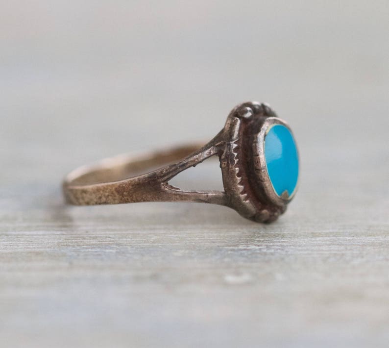May include: A silver ring with a turquoise stone set in a bezel setting. The ring has a simple band and a delicate design.