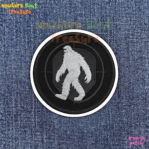 May include: Embroidered patch featuring a white Bigfoot figure within a black target design, set against a black background. The patch has a white border and the text "Nowhere Bout Treasure" and "iron-on patch".