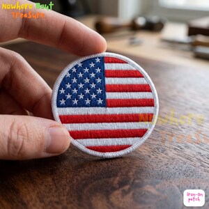 May include: Round iron-on patch featuring the American flag design. The patch has a white border, with red and white stripes and a blue field with white stars. The text "Iron-on patch" is visible.