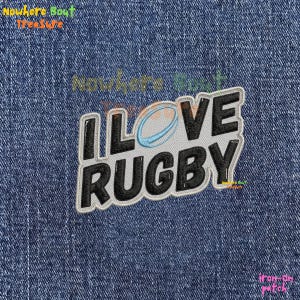 May include: An iron-on patch with the text "I LOVE RUGBY" in black, outlined in white, with a rugby ball graphic. The patch is on a blue denim background. The patch is a sports-themed item.
