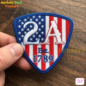 Puede incluir: Parche bordado con un diseño de escudo que presenta la bandera estadounidense, el texto "2A" y "Est. 1789". El parche tiene un borde azul y tiene forma de escudo. El parche es un parche termoadhesivo.