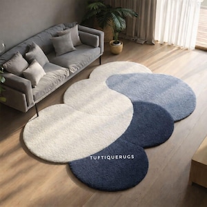 May include: A set of four round rugs in a flowing pattern. The rugs are in shades of white, light blue, medium blue, and navy blue. The text "TUFTIQUERUGS" is visible on the navy blue rug.