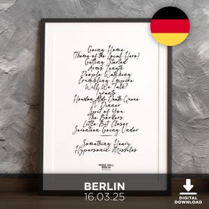 May include: A framed print featuring a handwritten setlist of songs, including "Going Home" and "Will We Talk?" The print has the text "BERLIN 16.03.25" at the bottom. A German flag is in the upper right corner.
