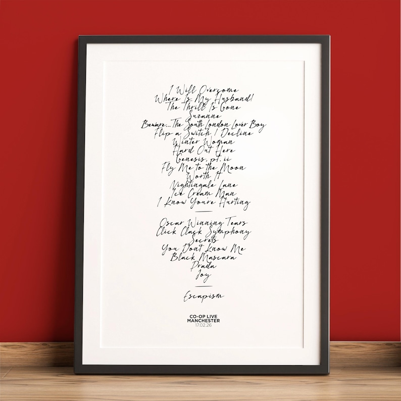 K&ouml;nnte beinhalten: Ein gerahmter Druck mit schwarzem Rahmen vor rotem Hintergrund. Der Druck zeigt handgeschriebene Songtitel in schwarzer Tinte, darunter "Escapism" und "Fly Me to the Moon". Der untere Teil des Drucks lautet "CO-OP LIVE MANCHESTER 17.02.26."