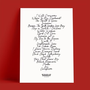 K&ouml;nnte beinhalten: Ein wei&szlig;es Poster mit handgeschriebenen Songtiteln in schwarzer Schrift, darunter "Fly Me to the Moon" und "Black Mascara". Das Poster enth&auml;lt auch den Text "BP PULSE LIVE BIRMINGHAM 23.02.26" am unteren Rand.