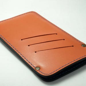 オレンジ色の革と青い糸のスリーブは、すべての携帯電話モデルにフィットします。カード、現金、ID用のポケットが3つあり、ベルトループ付きのイニシャルは不要です。