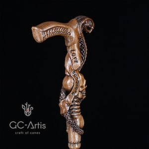 Another dark-background close-up of carved snake and skull handle. Highlights fine wood texture and polished detail. GC-Artis walking stick merges collectible fantasy design and functional craftsmanship.