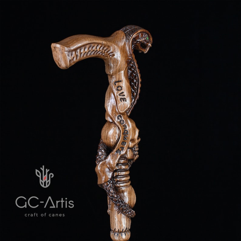 Another dark-background close-up of carved snake and skull handle. Highlights fine wood texture and polished detail. GC-Artis walking stick merges collectible fantasy design and functional craftsmanship.