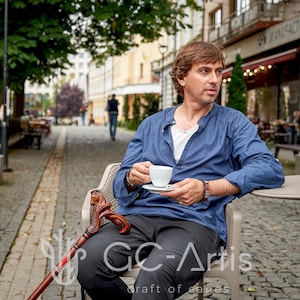 May include: A wooden walking cane featuring a detailed, hand-carved horse head handle with a polished dark brown finish. The cane has a smooth, tapered shaft and is positioned resting on a chair next to a person holding a white coffee cup.