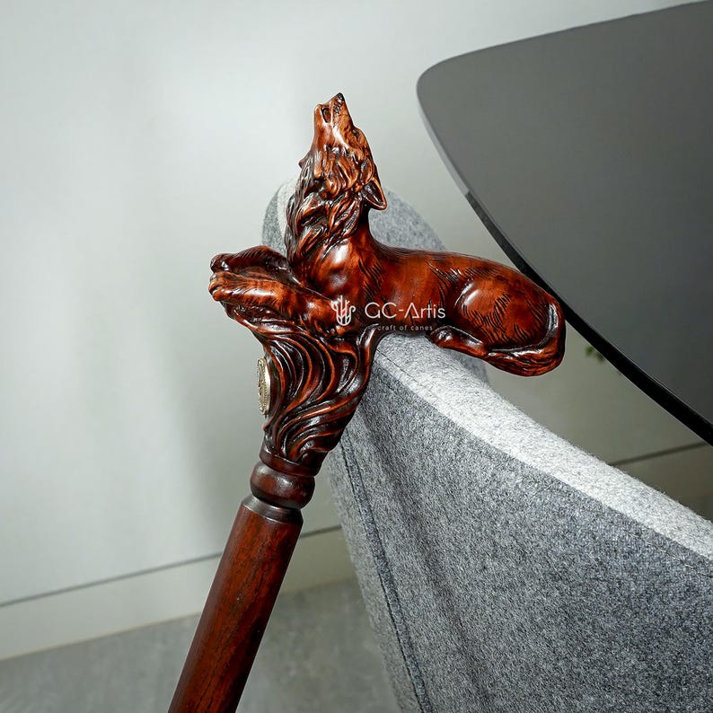 May include: A wooden walking stick with a carved wolf head handle. The wolf is howling and has a detailed, realistic design. The stick is brown and has a smooth finish.
