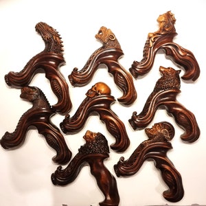 May include: Eight intricately carved wooden walking stick handles, each featuring a different animal or mythical creature. The handles are dark brown and have a detailed, flowing design.