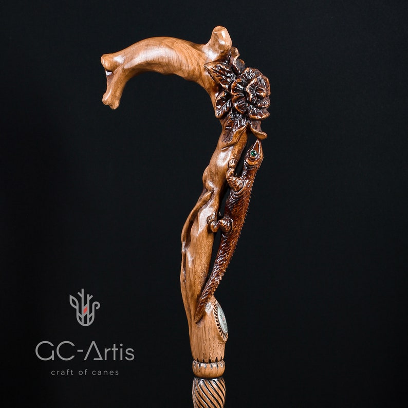 Studio photo of the Floral Lizard cane on a dark background. The rich wood tones, carved lizard figure and raised flowers appear in sharp contrast. The dark backdrop enhances the sculpted textures, showing how the handle’s artistic style stands out with depth, movement and elegant organic lines.