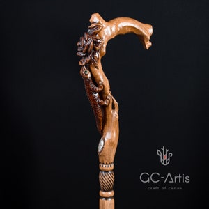 Studio photo of the Floral Lizard cane on a dark background showing the carved handle and upper shaft. The lizard figure rises from the top with curved movement and textured detail. Floral carvings blend with the warm wood surface, giving the cane a sculptural, organic aesthetic suitable for collectors and daily use.