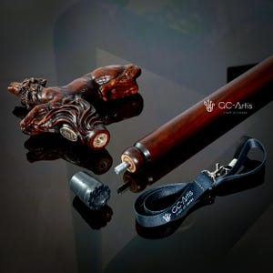 May include: A wooden walking stick with a carved horse head handle. The stick is disassembled and laid out on a black surface. The handle is a dark brown color and the stick is a lighter brown color. The stick also includes a black leather strap with a metal clasp and a black rubber tip.