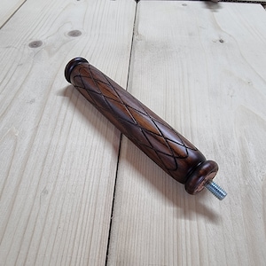 May include: A dark brown wooden furniture leg with a diamond-shaped carved pattern and a silver screw at the end.