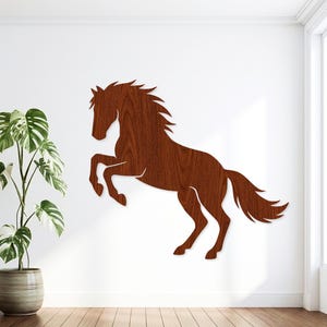 May include: A wall-mounted horse silhouette cutout crafted from dark brown wood with a visible grain pattern. The horse is depicted in a rearing position with its front legs lifted, a flowing mane, and a long tail, creating a flat decorative piece.