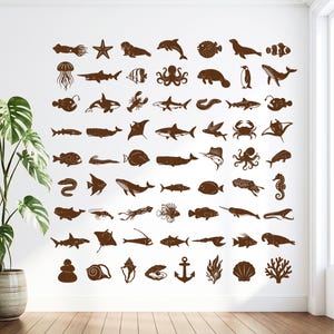 May include: A wall decal set featuring a collection of brown silhouettes of various marine life, including fish, whales, sharks, octopuses, jellyfish, crustaceans, and seashells, arranged in a grid pattern on a plain white wall surface.