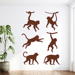 Op de afbeelding: Een set van zes donkerbruine houten apenmuurstickers in verschillende houdingen, waaronder hangend aan takken, springend en lopend. Elke figuur toont een zichtbare houtnerftextuur over het gehele oppervlak van de decoratieve figuren.