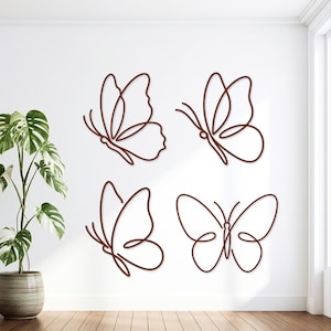 May include: A set of four brown wall-mounted butterfly decorations, each crafted from a single continuous line. The butterflies are displayed in different orientations, featuring simple, minimalist outlines that create a clean, modern aesthetic.