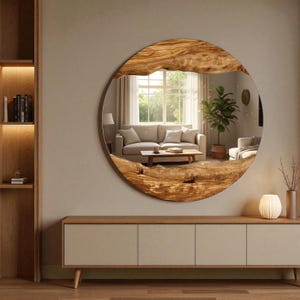 Peut inclure: Un miroir rond avec un cadre en bois naturel. Le miroir reflète un salon avec un canapé, une table basse et une fenêtre. Le cadre a une forme organique unique et une couleur marron chaude.