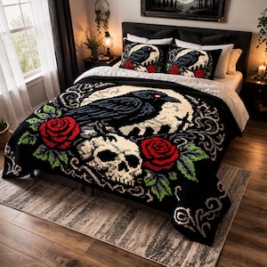 May include: A black and white gothic-themed bedspread featuring a large raven, skull, and red roses. Two matching throw pillows with a raven and rose design are on the bed. The bed is made up with white sheets and a dark gray headboard.