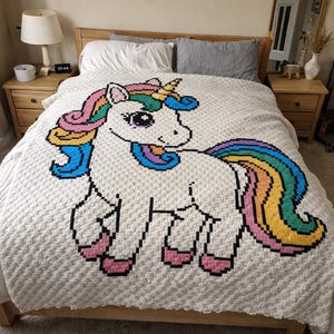 May include: A white crochet blanket featuring a colorful unicorn design. The unicorn has a rainbow mane and tail, with pink, blue, yellow, and green accents. The blanket is on a bed with wooden furniture.