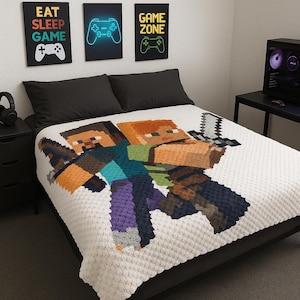 Puede incluir: Una manta blanca texturizada con personajes pixelados de videojuegos. Encima de la cama hay tres obras de arte enmarcadas con las palabras "EAT SLEEP GAME" y "GAME ZONE". También se ve una torre de ordenador y unos auriculares.