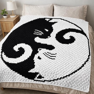 Könnte beinhalten: Eine schwarz-weiße Häkeldecke mit einem Yin-Yang-Design mit zwei Katzen. Eine Katze ist schwarz und die andere weiß, wobei die Körper der Katzen die kreisförmige Form bilden. Die Decke liegt auf einem Bett mit einer neutralfarbenen Tagesdecke.