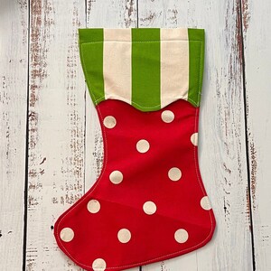 May include: Red and white Christmas stocking with green and white striped cuff. The stocking is decorated with white polka dots.