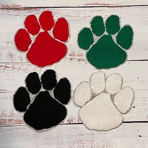 May include: Four felt paw prints in different colors: red, green, black, and white. Each paw print has a glittery outline.