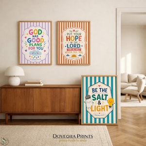 Three framed prints with Christian sayings and playful illustrations hang on a wall.
