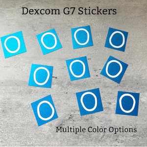 May include: A collection of blue square stickers with a white circular design. The text "Dexcom G7 Stickers" is at the top, and "Multiple Color Options" is at the bottom. The stickers are scattered on a gray surface.