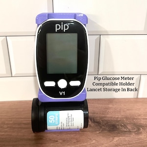 May include: A black and white Pip glucose meter with a purple holder, and a black vial of 50 test strips. The meter has a digital display and white buttons. The text "Pip" and "V1" are visible.