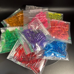 May include: Assortment of colorful plastic pieces in clear plastic bags. Each bag is labeled "1/4 CUP" and "Portion Pack." Colors include red, orange, yellow, green, purple, blue, and pink. The pieces appear to be small, cylindrical, and translucent.