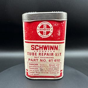 May include: Vintage Schwinn Tube Repair Kit in a red and white metal container. The container has a silver lid and features the Schwinn logo and product information. The text on the container includes "Self Vulcanizing" and "Part No. 60 410".