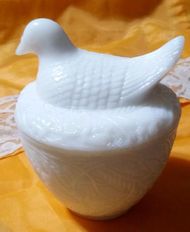 May include: A white, vintage-style trinket box shaped like a bird on a nest. The bird has detailed feathering, and the nest-shaped base features a leaf pattern. The lid lifts off to reveal the interior, perfect for storing small items.