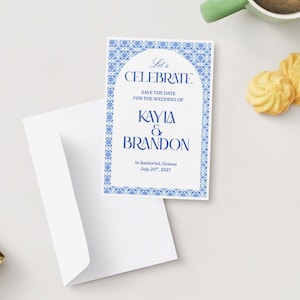Könnte beinhalten: Eine Hochzeitseinladung mit blau-weißem Zierrand und dem Text "Let's CELEBRATE" und "KAYLA & BRANDON". Die Einladung wird von einem weißen Umschlag und zwei Keksen begleitet.