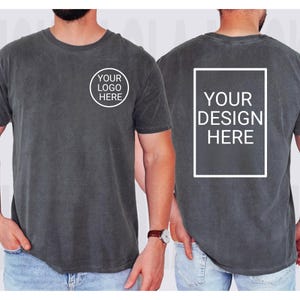 Puede incluir: Camiseta gris carb&oacute;n con cuello redondo. La parte delantera presenta un c&iacute;rculo blanco con el texto "YOUR LOGO HERE". La parte trasera de la camiseta tiene un rect&aacute;ngulo blanco con el texto "YOUR DESIGN HERE".