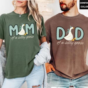 May include: Two short-sleeved t-shirts, one olive green and one brown. The olive green shirt says "MOM of a silly goose" with a goose graphic. The brown shirt says "DAD of a silly goose" with a goose graphic. Both shirts have a similar design.