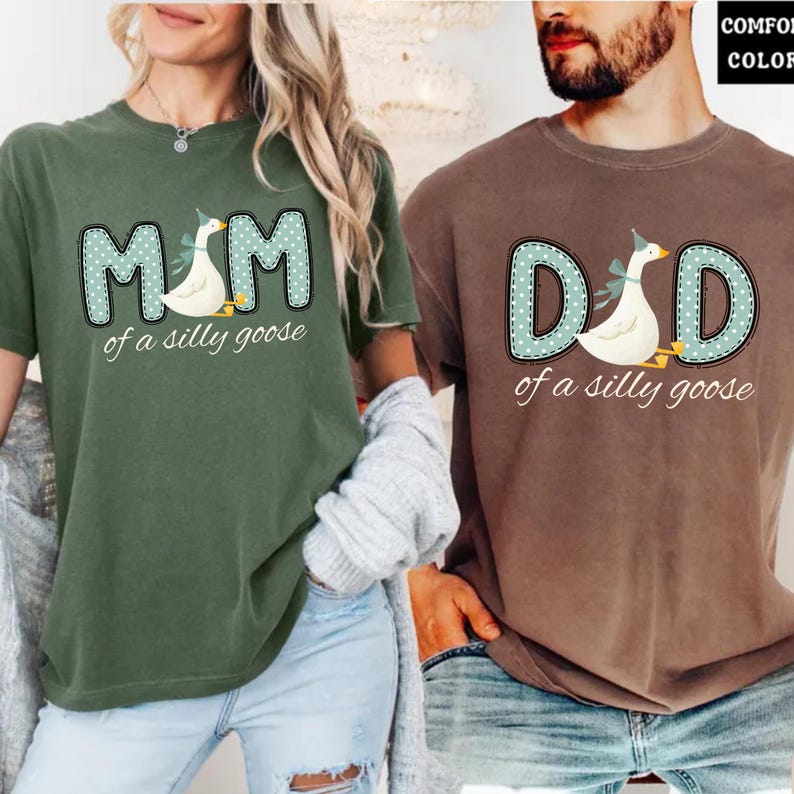 May include: Two short-sleeved t-shirts, one olive green and one brown. The olive green shirt says "MOM of a silly goose" with a goose graphic. The brown shirt says "DAD of a silly goose" with a goose graphic. Both shirts have a similar design.